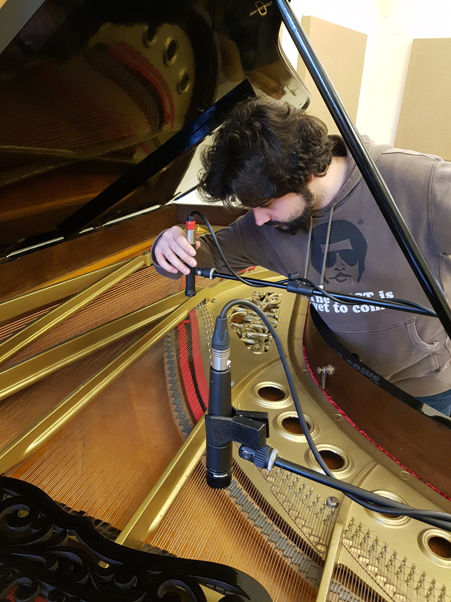 Ivan Zora che posiziona i microfoni su un pianoforte a coda